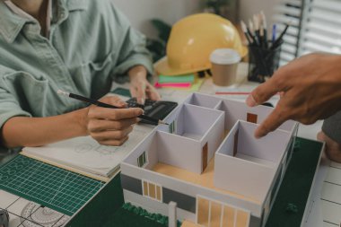 Mühendis ve yatırımcı, yakında inşa edilecek bir konut projesinin detaylarını görüşüyorlar. Bir mimar, müşterinin ihtiyaçlarını karşılayacak bir ev yapısı tasarlamak için bir mühendise danışıyor.