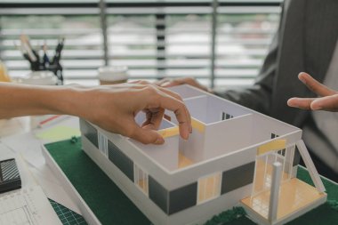 Bir ustabaşı ev yapısı hakkında bir mühendise danışıyor, n mimarı ve asistanı planlar, toplantı, proje, tartışma, takım çalışması hakkında beyin fırtınası yapıyor ve inceliyor.