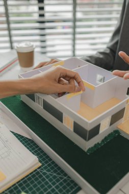 Bir ustabaşı ev yapısı hakkında bir mühendise danışıyor, n mimarı ve asistanı planlar, toplantı, proje, tartışma, takım çalışması hakkında beyin fırtınası yapıyor ve inceliyor.