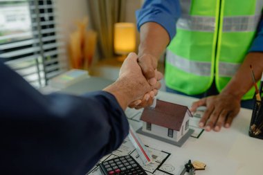 Mühendis ve mimar kutlamak için el sıkışıyorlar çünkü büyük inşaat projesini yeni bitirdiler. Toplantıdan sonra iki mühendis tokalaşıyor.