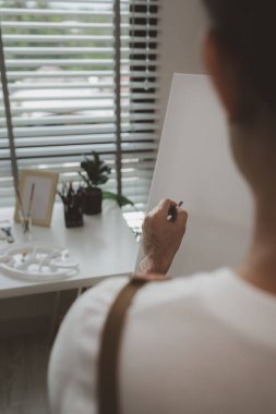Bir sanatçı kendi resim stüdyosunda tuval, palet, suluboya, yağlar, poster renkleri, sanatsal, ressam, renkler, yaratıcılık, beceri gibi çeşitli resim aletleriyle oturuyor.