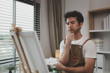 Bir ressam resim stüdyosunda, yükselen bir erkek sanatçı hem resim, palet, tuval, boya, yağlı boya boya, poster renkleri gibi en iyi tablolarını yapmaya odaklanıyor..