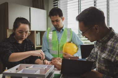 Mühendislerden oluşan bir ekip, tasarım yapısını analiz etmek ve müşterinin isteklerini karşılamak için ofiste toplanıyor. Mimarlar ve müteahhitlerden oluşan bir ekip, bir model eve dayanan tasarımı tartışmak için toplanıyor..