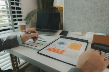 Bir işadamı özel ofisinde ve bir sürü evrak işiyle uğraşıyor. Pazarlama şirketinin üst düzey yöneticilerinden biri bu yılın gelir raporlarını inceliyor.