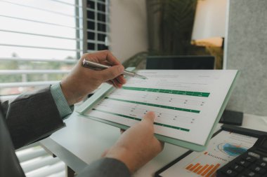 Bir işadamı özel ofisinde ve bir sürü evrak işiyle uğraşıyor. Pazarlama şirketinin üst düzey yöneticilerinden biri bu yılın gelir raporlarını inceliyor.