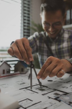 Mühendislerden oluşan bir ekip, tasarım yapısını analiz etmek ve müşterinin isteklerini karşılamak için ofiste toplanıyor. Mimarlar ve müteahhitlerden oluşan bir ekip, bir model eve dayanan tasarımı tartışmak için toplanıyor..
