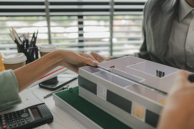 Bir mimar ve asistanı beyin fırtınası yapıyor ve planları inceliyor, iki mühendis yapıyı güçlendirmek, taslak, toplantı, takım çalışması yapmak için bir inşaat planını tartışıyorlar.