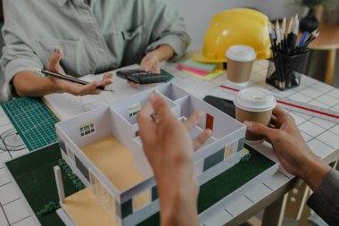 Mühendis ve yatırımcı, yakında inşa edilecek bir konut projesinin detaylarını görüşüyorlar. Bir mimar, müşterinin ihtiyaçlarını karşılayacak bir ev yapısı tasarlamak için bir mühendise danışıyor.