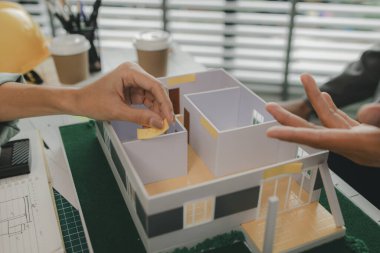 Bir ustabaşı ev yapısı hakkında bir mühendise danışıyor, n mimarı ve asistanı planlar, toplantı, proje, tartışma, takım çalışması hakkında beyin fırtınası yapıyor ve inceliyor.