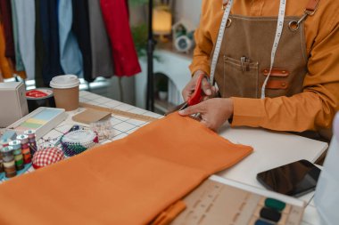 Tasarımcı dükkanının sahibi stüdyosunda çalışıyor, kıyafet yapmak için çok kumaş kullanıyor, müşteri için şık kıyafetler tasarlıyor, dikiş tasarımı tasarımcı için önemli bir araçtır..