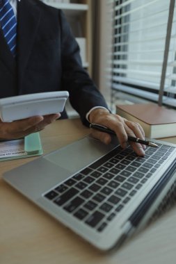Bir işadamı elinde belgelerle bir ofiste oturmuş verileri analiz ediyor. Bir şirketin yöneticisi şirket sahibi olarak itibarını göstermek için takım elbise giyer..