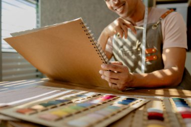 Bir terzi, stüdyosunda mutlu bir şekilde bir elbise çiziyor. Bir moda tasarımcısı, yeni koleksiyonunu eskiz kağıdına çiziyor. Elbiselerini, kıyafetlerini, modasını, modasını, modasını...