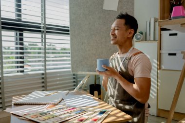 Bir moda tasarımcısı bütün sabah çalıştıktan sonra dikiş atölyesinde mola veriyor. Bir terzi boş zamanını, tasarım ve dikiş malzemeleriyle dolu olan atölyesinde geçiriyor.