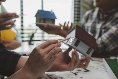 Mühendislerden oluşan bir ekip, tasarım yapısını analiz etmek ve müşterinin isteklerini karşılamak için ofiste toplanıyor. Mimarlar ve müteahhitlerden oluşan bir ekip, bir model eve dayanan tasarımı tartışmak için toplanıyor..