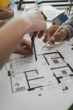 Mühendislerden oluşan bir ekip, tasarım yapısını analiz etmek ve müşterinin isteklerini karşılamak için ofiste toplanıyor. Mimarlar ve müteahhitlerden oluşan bir ekip, bir model eve dayanan tasarımı tartışmak için toplanıyor..