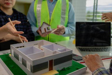 Mühendisler ve müteahhitler tasarım ve inşaatta ortaya çıkan sorunları çözmek için işbirliği yapıyorlar. Mimarlar, müşterinin ihtiyaçlarını karşılamak için tasarım yapısını incelemek üzere ofiste buluşuyorlar..