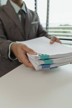 Bir ofis çalışanı her şeyi güvende tutmak için önemli belgeleri bir araya getiriyor. Bir iş adamı önemli iş belgelerini düzgün bir yere koyuyor. Belgeler ve raporlar.