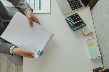 Bir ofis çalışanı her şeyi güvende tutmak için önemli belgeleri bir araya getiriyor. Bir iş adamı önemli iş belgelerini düzgün bir yere koyuyor. Belgeler ve raporlar.