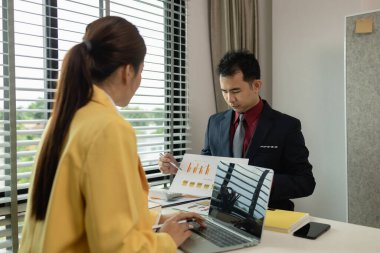 İş adamı ve iş kadını özel bir ofiste birlikte otururlar. İki meslektaş etkili bir şekilde bir takım olarak birlikte çalışırlar. Meslektaşlar arasındaki iş toplantısı.