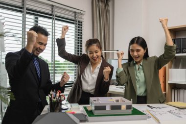 Bir grup mimar, iş başarıyla tamamlandıktan sonra birbirlerini tebrik ediyor. Bir mimarlık firmasının kurucuları, bir inşaat anlaşmasını başarıyla sonuçlandırdıktan sonra kutlama yapıyorlar.