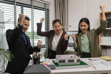 Bir grup mimar, iş başarıyla tamamlandıktan sonra birbirlerini tebrik ediyor. Bir mimarlık firmasının kurucuları, bir inşaat anlaşmasını başarıyla sonuçlandırdıktan sonra kutlama yapıyorlar.