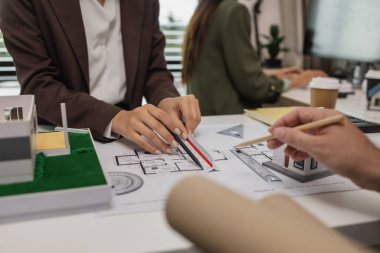 Mimarlar, ilk taslak planın doğruluğunu kontrol etmek için ofiste mühendis ve müteahhitlerle birlikte çalışırlar. Masanın üzerindeki plan, üç mimar iş yerinde birlikte çalışırlar.