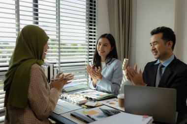 Bir grup iş adamı bir ofiste tartışıyorlar. Farklı kültürlerden iş adamları uygun ve dini açıdan doğru ürünler üretmek için toplanıyorlar. Bir iş kadını başörtüsü takıyor..