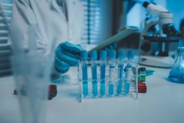 Bir kimyager laboratuvarda bir sıvı örneğini inceler, bilimsel deney ekipmanları, mikroskop, kadın bilim adamı, kadın kimyager ve araştırmacı bilimsel araştırmalar yapar.