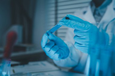 Bir kimyager laboratuvarda bir sıvı örneğini inceler, bilimsel deney ekipmanları, mikroskop, kadın bilim adamı, kadın kimyager ve araştırmacı bilimsel araştırmalar yapar.