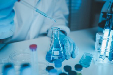 Bir kimyager laboratuvarda bir sıvı örneğini inceler, bilimsel deney ekipmanları, mikroskop, kadın bilim adamı, kadın kimyager ve araştırmacı bilimsel araştırmalar yapar.