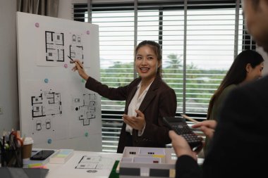 Ofiste bir mimar ekibiyle birlikte çalışıyor, planlar masanın üzerinde, müteahhit mühendislik ve mimari ile çalışıyor, ev modeli de masanın üstünde.