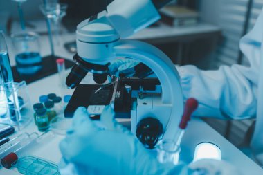 Bir kimyager laboratuvarda bir sıvı örneğini inceler, bilimsel deney ekipmanları, mikroskop, kadın bilim adamı, kadın kimyager ve araştırmacı bilimsel araştırmalar yapar.