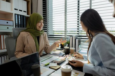 Bir grup iş adamı bir ofiste tartışıyorlar. Farklı kültürlerden iş adamları uygun ve dini açıdan doğru ürünler üretmek için toplanıyorlar. Bir iş kadını başörtüsü takıyor..