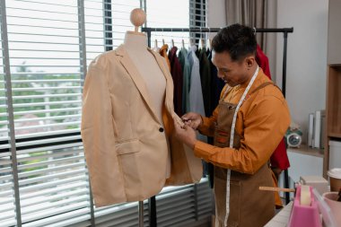 Bir tasarımcı atölyesinde çalışıyor, alışverişe gönderilmeden önce tüm kıyafetleri kontrol ediyor, yetenekli tasarımcı işinden memnun, şık. kumaş, dikiş, moda, girişimci