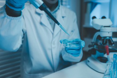 Bir kimyager laboratuvarda bir sıvı örneğini inceler, bilimsel deney ekipmanları, mikroskop, kadın bilim adamı, kadın kimyager ve araştırmacı bilimsel araştırmalar yapar.