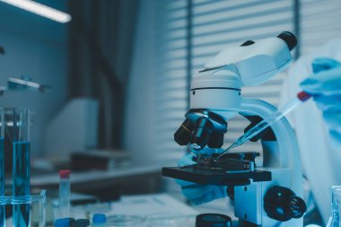 Bir kimyager laboratuvarda bir sıvı örneğini inceler, bilimsel deney ekipmanları, mikroskop, kadın bilim adamı, kadın kimyager ve araştırmacı bilimsel araştırmalar yapar.