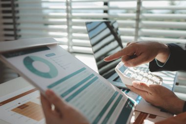 Gün boyunca bir ofiste çalışan bir çalışan masasında iş arkadaşlarıyla birlikte çalışıyor. Girişimciler şirketteki belgelerle çalışıyorlar.