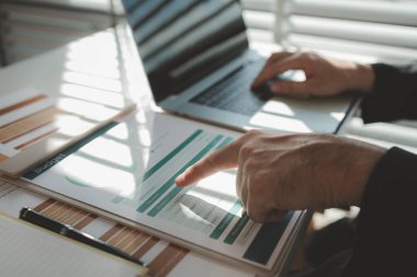 Gün boyunca bir ofiste çalışan bir çalışan masasında iş arkadaşlarıyla birlikte çalışıyor. Girişimciler şirketteki belgelerle çalışıyorlar.