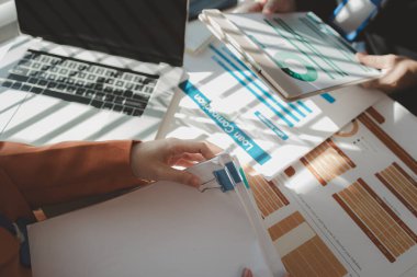 Gün boyunca bir ofiste çalışan bir çalışan masasında iş arkadaşlarıyla birlikte çalışıyor. Girişimciler şirketteki belgelerle çalışıyorlar.