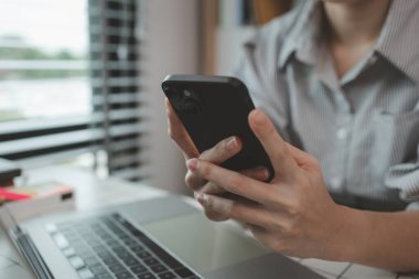 Bir iş kadını ekibine bilgi göndermek için elektronik bir cihaz kullanıyor. Pazarlama ekibi lideri, pazarlama verileriyle ilgili belgeleri inceliyor.