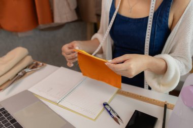 Atölyede dikiş malzemeleri kullanan kadın moda tasarımcısı, kumaş atölyesinde çalışan genç bir kadının portresi, atölyesinde çalışan genç bir terzi manzarası.