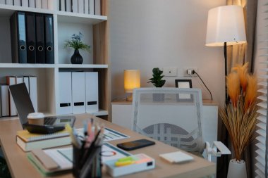 Açık dizüstü bilgisayarı, verimli çalışma ortamı, şık ahşap masası, modern ofis alanı ve profesyonel çalışma ortamı olan güneşli bir ofis masası..