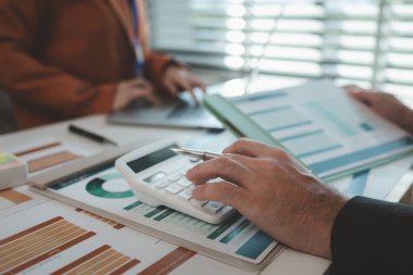 Çalışanlar, iş bitmeden önce tamamlanması gereken bir yığın belgeyle bir ofiste otururken, girişimciler yatırımcılara sunum hazırlamak için işlerini planlıyorlar.