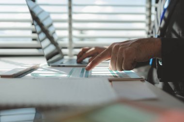 Gün boyunca bir ofiste çalışan bir çalışan masasında iş arkadaşlarıyla birlikte çalışıyor. Girişimciler şirketteki belgelerle çalışıyorlar.