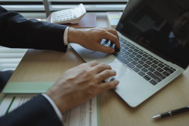 Bir işadamı elinde belgelerle bir ofiste oturmuş verileri analiz ediyor. Bir şirketin yöneticisi şirket sahibi olarak itibarını göstermek için takım elbise giyer..