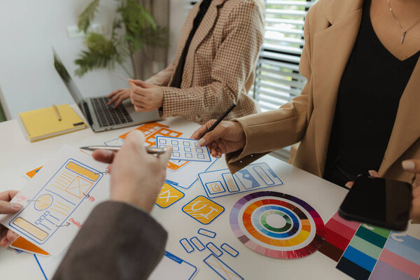 Дизайнеры цифровых продуктов обмениваются идеями в своих офисах о том, как создать веб-сайт, отвечающий потребностям современных пользователей, которые сосредоточены на простоте использования и красивых цветах.