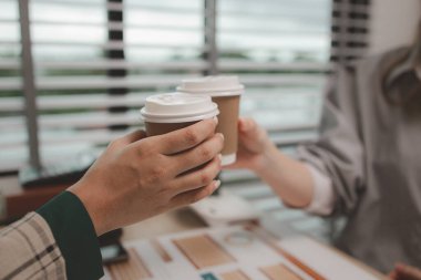 İki kadın çalışan bir projeyi başarıyla tamamladıktan sonra kutlama yapıyorlar. Ofiste başarıyı kutlayan iş adamları, toplantı odasında tokalaşan neşeli iş kadınları.,