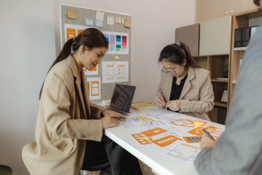 Web geliştiricilerinden oluşan bir ekip bir web sitesi planının en iyi nasıl düzenleneceğini tartışıyor. Dijital bir ürünü en iyi nasıl optimize edeceklerine dair fikirleri paylaşıyorlar.