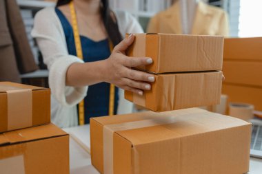 Tasarımcı müşterilere postayla gönderilecek ürünler hazırlıyor, kadın terzi de gelirini artırmak için ürünlerini internette satıyor, kadın endüstriyel terzi.