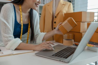 Tasarımcı müşterilere postayla gönderilecek ürünler hazırlıyor, kadın terzi de gelirini artırmak için ürünlerini internette satıyor, kadın endüstriyel terzi.